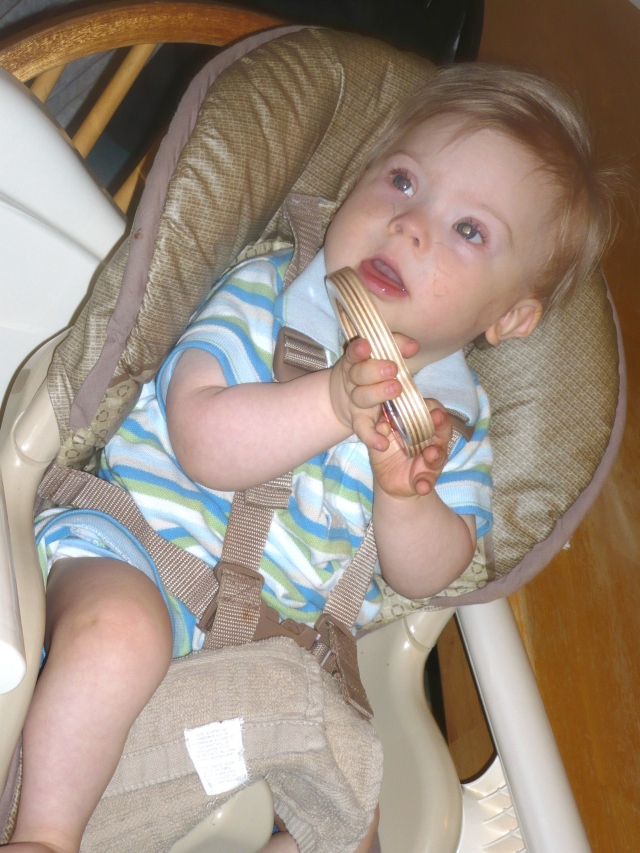 Raphael in his high chair propped with a towel between his knees