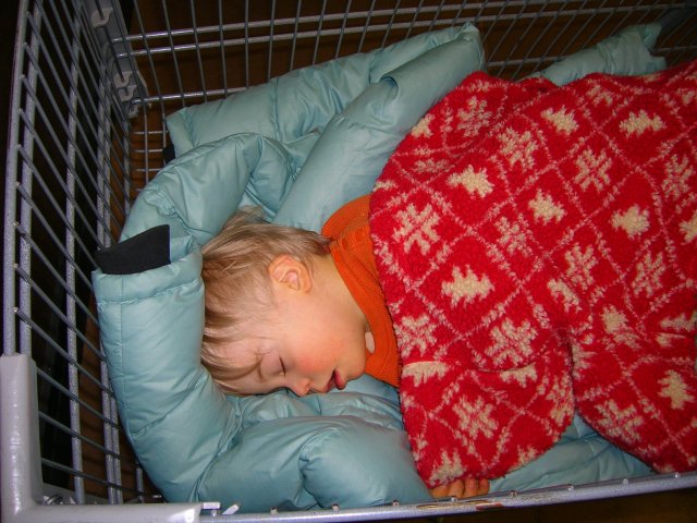 Little boy crashed out in a shopping cart.