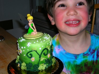Elijah grins next to his green Tinkerbell cake.